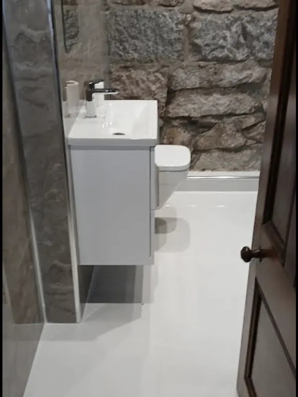 Wall-hung vanity basin and toilet fitted against an exposed granite wall